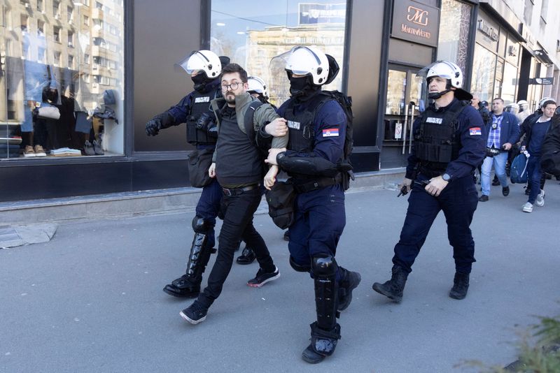 Police officers detain people during a protest in Belgrade